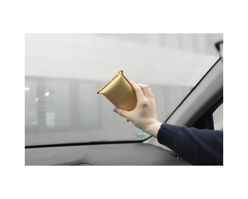 Eine Person reinigt eine Autoscheibe mit einem Reinigungspad.