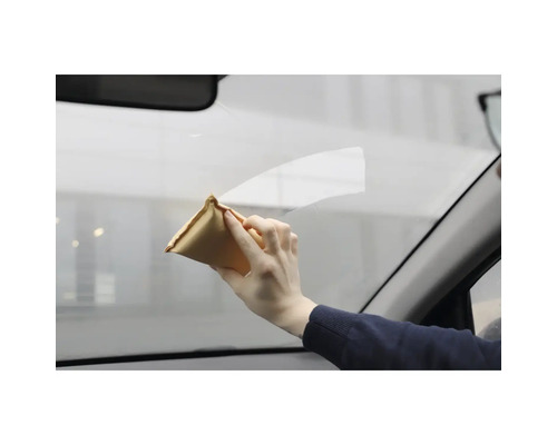 Eine Person reinigt eine Autoscheibe mit einem Reinigungstuch.