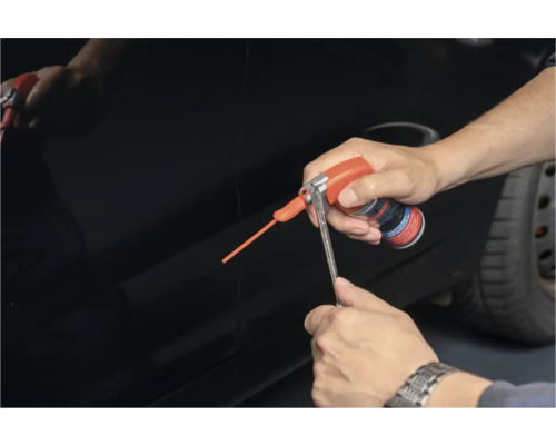 Eine Person verwendet Rostlöser auf einem Fahrzeug.