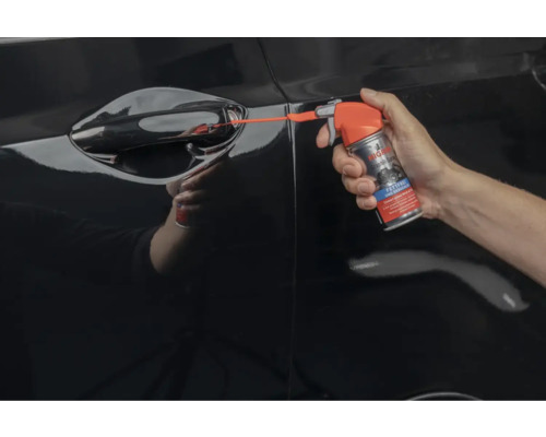 Eine Person sprüht mit einem Türschlossenteiser in ein Autoschloss.