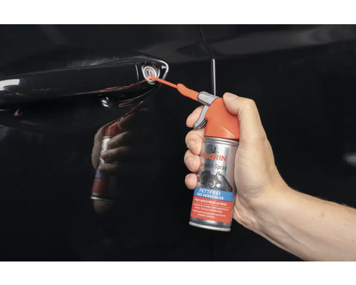 Eine Person sprüht Graphitspray in ein Autoschloss.