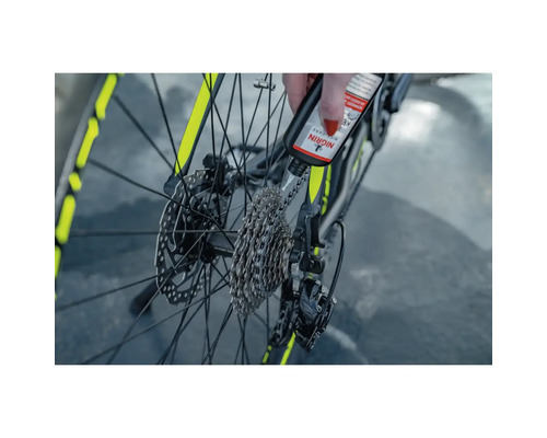 Auftragen von Nigrin Kettenöl auf eine Fahrradkette für die Wartung