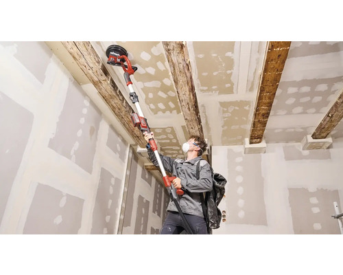 Mann schleift Decke mit einem Deckenschleifer in einem Raum