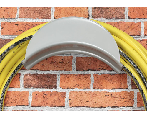 Gelber Gartenschlauch auf Schlauchhalter an einer Ziegelwand