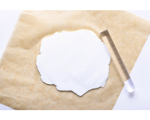Weiße Modelliermasse mit Acrylroller auf Backpapier