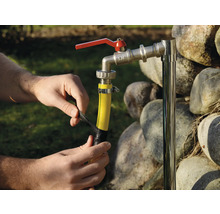 Person befestigt einen Gartenschlauch an einem Wasserhahn mit Isolierband.