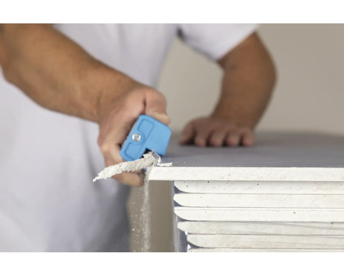 Handwerker entgratet Gipskartonplatte mit Entgrater