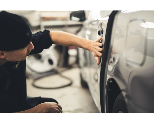 Ein Mann überprüft die Autotür auf Beschädigungen.