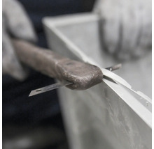 Auftragen von Dichtmasse mit einem Messer auf ein Fenster