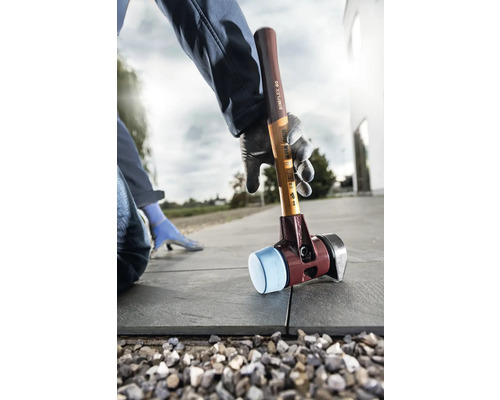 Mann verlegt Pflastersteine mit Schonhammer