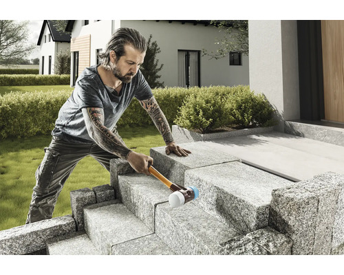 Mann verlegt Steintreppe mit Gummihammer im Garten eines Hauses
