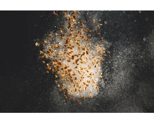 Explosion von Granulat und Staub vor dunklem Hintergrund