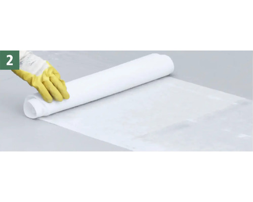 Eine Person rollt eine weiße Abdeckplane aus, um den Boden zu schützen.