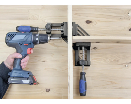 Eine Person verschraubt mit einem Akkubohrer ein Werkstück, das mit einer Eckspannzwinge fixiert ist.