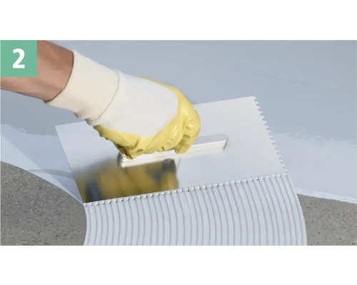 Eine Person, die mit einer Zahnspachtel Klebstoff aufträgt.