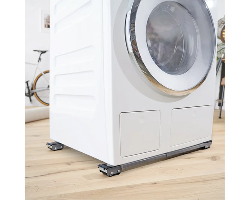 Waschmaschine auf einem Maschinenfuß mit Rollen auf Holzboden