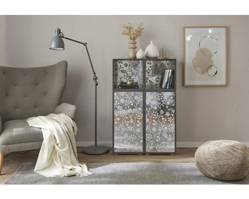 Wohnzimmer-Szene mit Sessel, Stehlampe, Teppich, Hocker und Regal mit floralem Muster