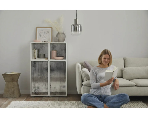 Wohnzimmer mit Regalen, Dekoration, Pendelleuchte, Sofa und einer Frau, die ein Buch liest.