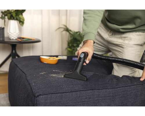 Reinigung eines Stoffhockers mit Staubsaugerdüse