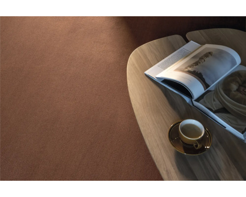 Nahaufnahme von einem Teppich neben einem Tisch mit einer Tasse und einer Zeitschrift