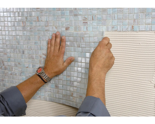Mosaikfliesen werden an der Wand verlegt