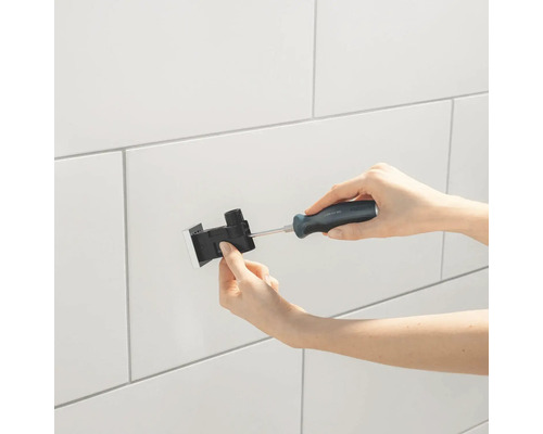 Person montiert ein Produkt mit einem Schraubendreher an einer Wand.