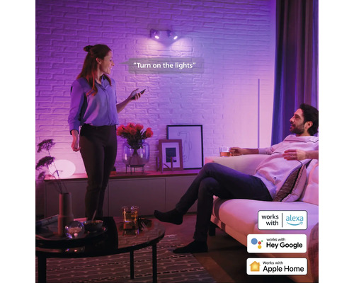 Wohnzimmer mit zwei Personen, die Smart Home Beleuchtung mit Sprachsteuerung nutzen