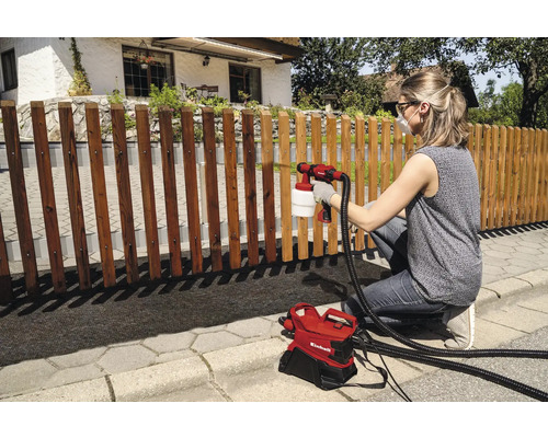 Frau sprüht Holzzaun mit Farbsprühsystem von Einhell