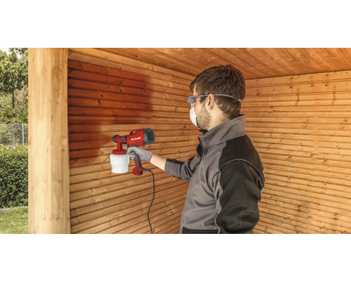 Mann sprüht Holz mit einer Farbspritzpistole