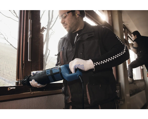 Ein Handwerker demontiert mit einer Säbelsäge ein Fenster.