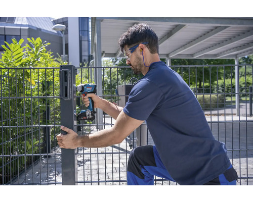 Mann montiert einen Zaunpfosten mit einem Akku-Bohrschrauber.