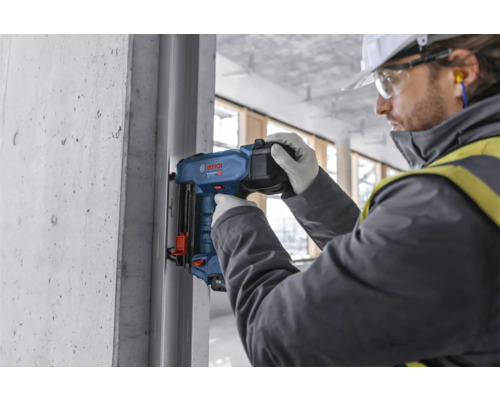 Ein Arbeiter verwendet einen Bolzensetzgerät auf einer Baustelle.