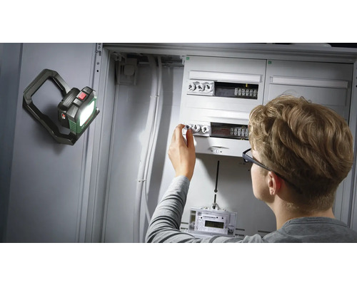 Elektriker arbeitet an Sicherungskasten mit LED-Arbeitsleuchte