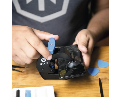 Ein Mann repariert ein Smartphone mit einem Werkzeug von iFixit.