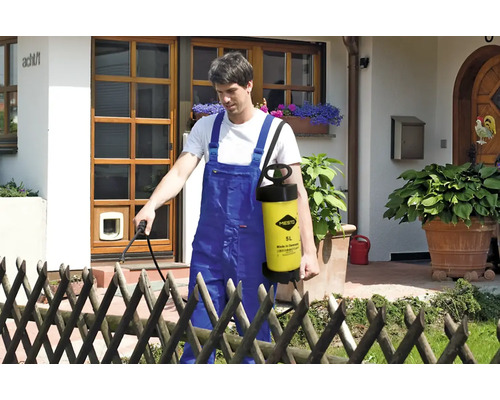 Mann benutzt eine Mesto Gartenspritze zur Gartenarbeit vor einem Haus.