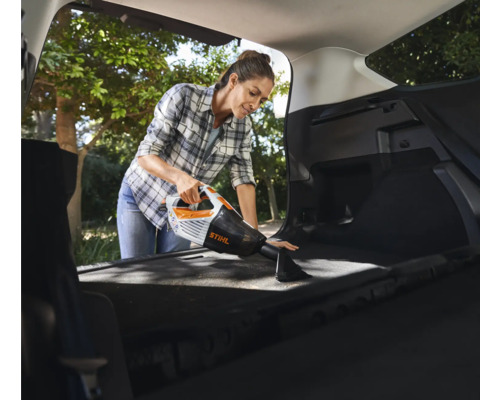 Frau reinigt Kofferraum mit Akku-Handsauger von Stihl