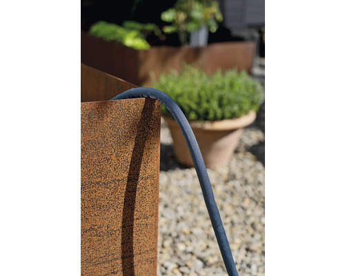 Gartenszene mit Pflanzgefäßen und einem flexiblen Gartenschlauch