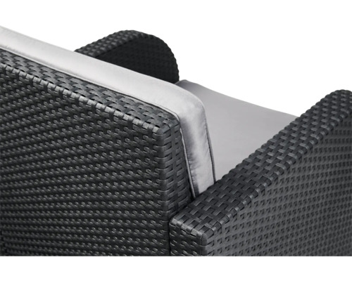 Detailansicht eines schwarzen Rattansofas mit grauen Polstern.
