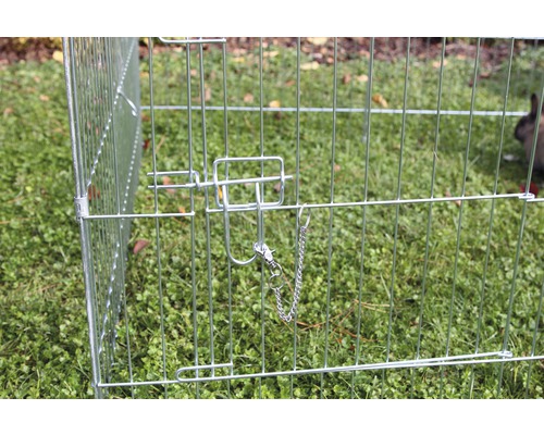 Nahaufnahme eines Drahtkäfigs mit Verriegelungsmechanismus für Kleintiere im Garten.