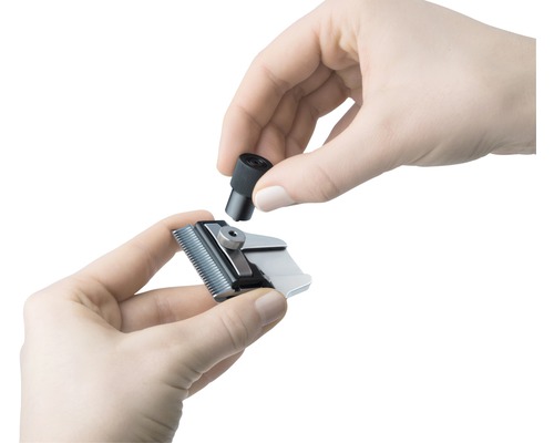 Zwei Hände setzen einen schwarzen Knopf auf einen Scherkopf.