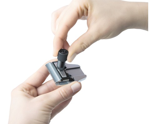 Eine Person justiert den Schneidsatz einer Haarschneidemaschine.