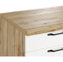 Detailaufnahme eines Schranks mit Holzstruktur und weißen Schubladen