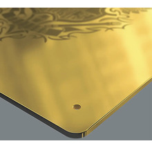 Detailansicht einer goldenen Metallplatte mit Ornament und Bohrloch.