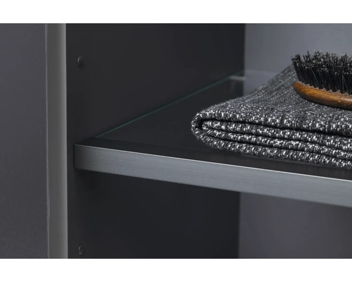 Detailansicht eines Badezimmerschranks mit Glasregal, Handtuch und Bürste