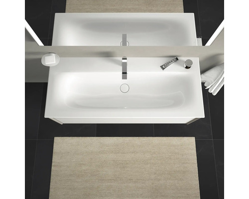 Aufnahme von oben eines Badezimmers mit Waschbecken, Spiegel, Armatur, Seifenspender, Zahncreme, Handtuch und Badematte