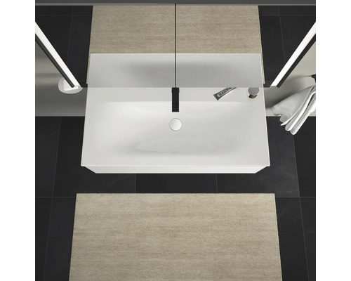 Aufsicht auf ein Badezimmer mit Waschbecken, Armatur, Spiegel, Badematten und Handtuch