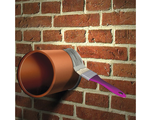 Anstreichen eines Rohres an einer Ziegelwand mit einem Pinsel