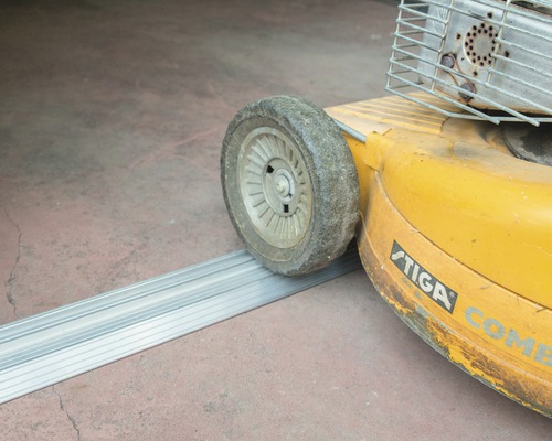Rad eines Rasenmähers überfährt eine Aluminiumrampe