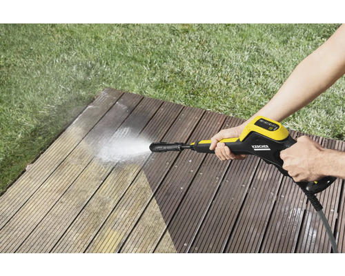 Person reinigt Holzterrasse mit Hochdruckreiniger der Marke Kärcher