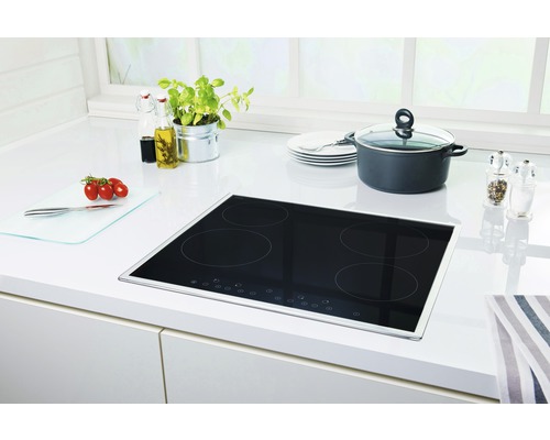 Schwarzes Kochfeld auf einer Küchentheke mit Kochtopf und Zutaten